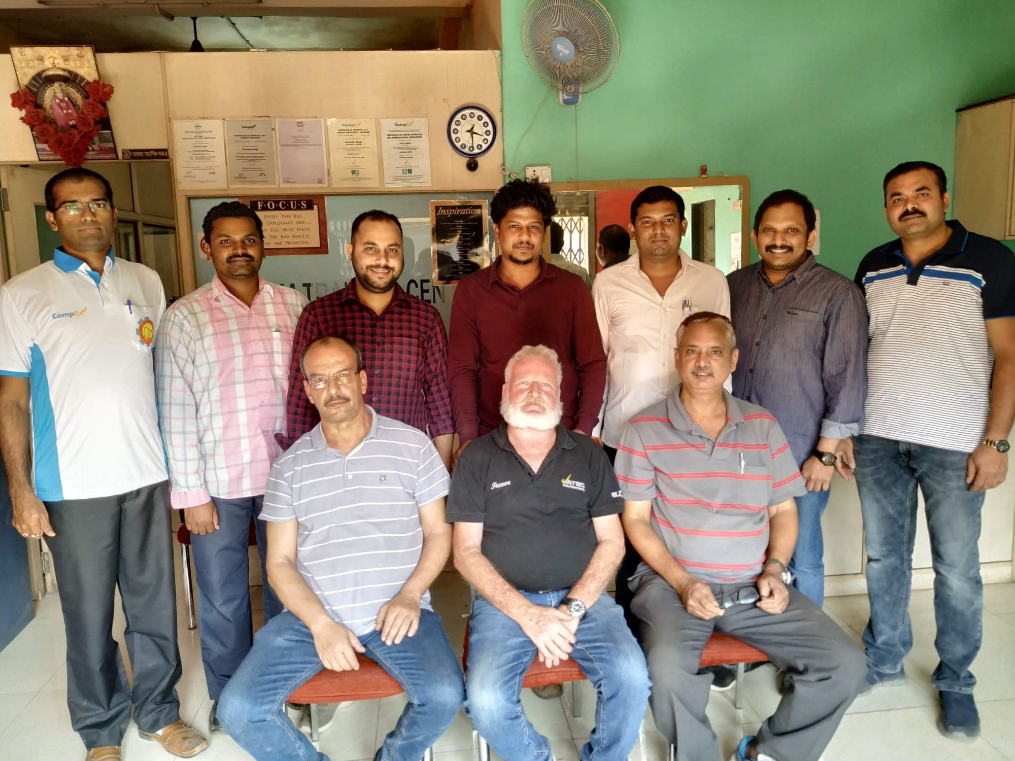 Eleven engineers with their trainer in the centre's reception at the end of a course, three of them seated at the front.